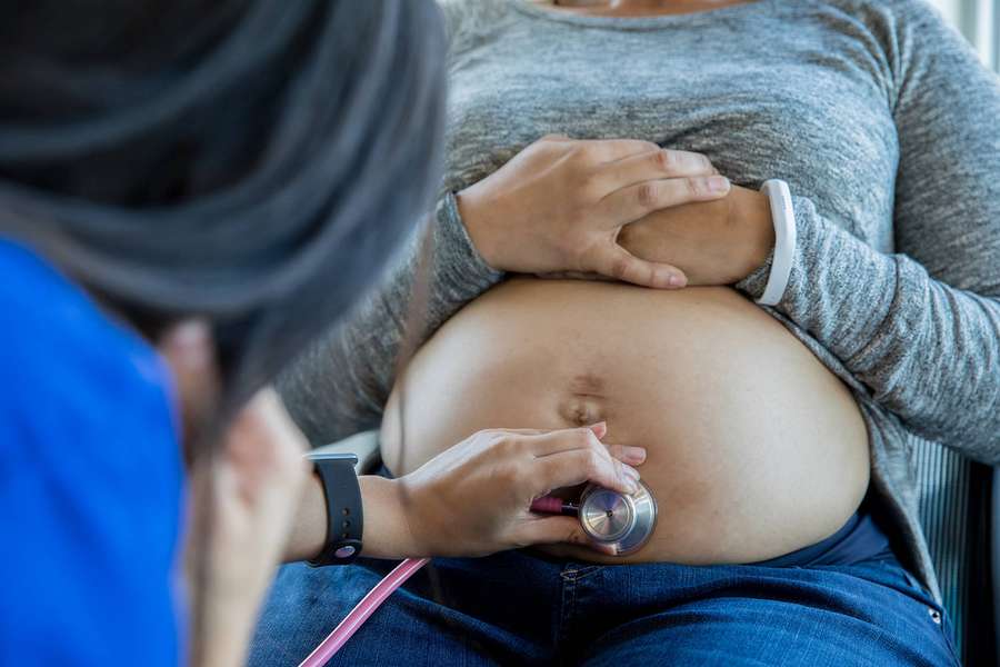 Arzt hört mit Stethoskop den Herzschlag des Babys auf dem Bauch einer schwangeren Frau. — Schwangerer Bauch Wallpaper