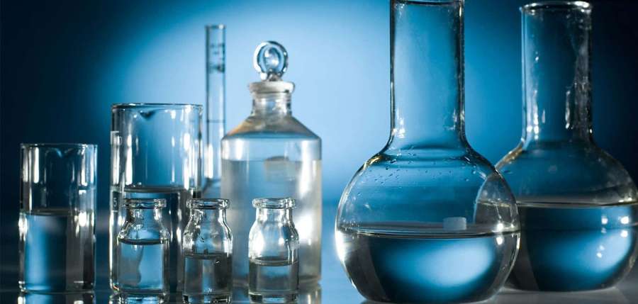 Scientific glassware filled with liquid under blue light on reflective surface — Science Lab Background