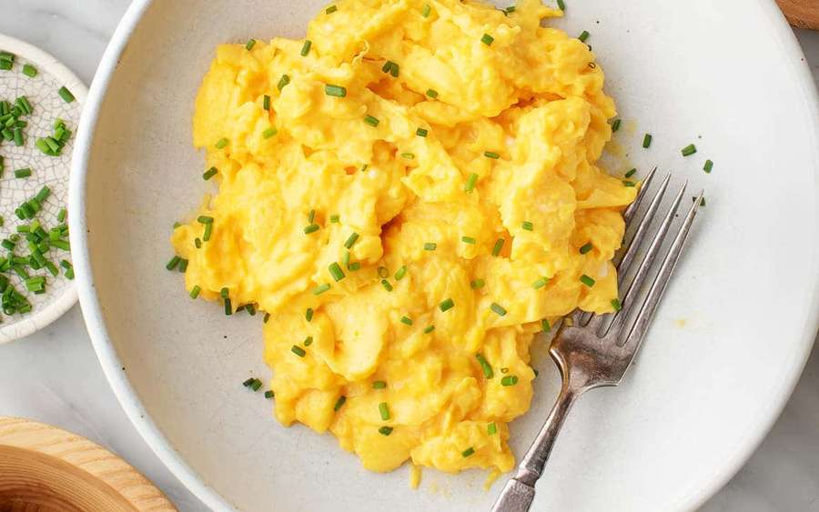 Scrambled eggs with chives in a white bowl with a fork. — Scrambled Egg Picture