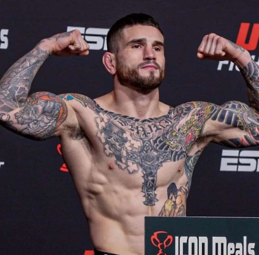 Tattooed MMA fighter flexing at weigh-in event with ESPN and ICON Meals logos. — Sean Brady Wallpaper