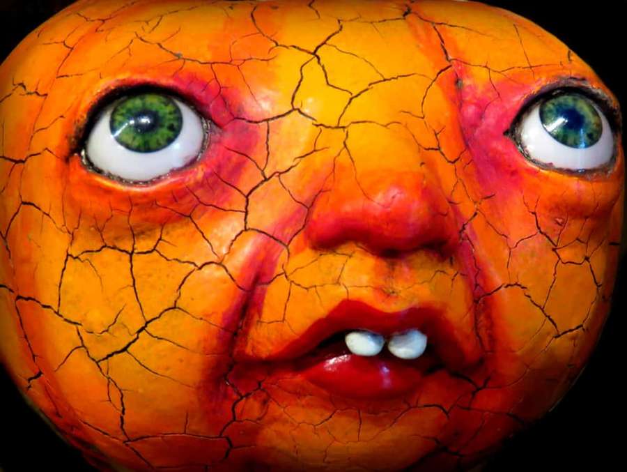 Ein rissiges orangefarbenes bemaltes Gesicht mit grünen Augen und roten Lippen. — Seltsame Profilbilder