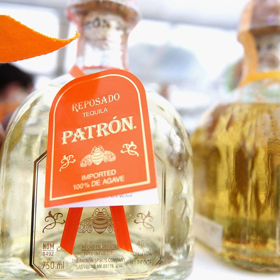 Primo piano di bottiglia di tequila Patrón Reposado con etichetta arancione e design dell'ape. — Sfondo patrono Sfondi