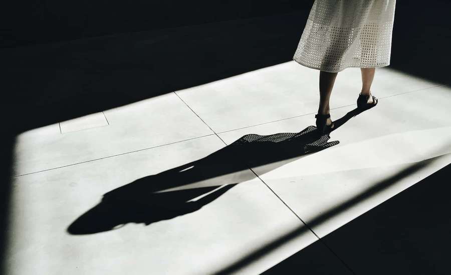A person in a white dress casts a long shadow on a tiled floor in a dark room. — Shadow Picture