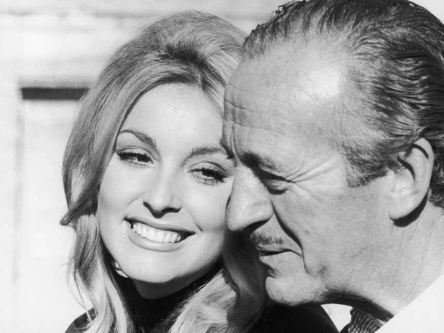 A smiling woman and a man with a mustache in a close-up black and white photo. — Sharon Tate Background