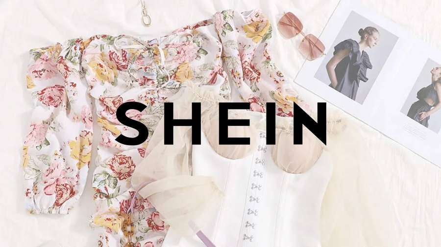 Floral blouse and sheer white clothing styled on a bed with sunglasses and fashion magazines. — Shein Background