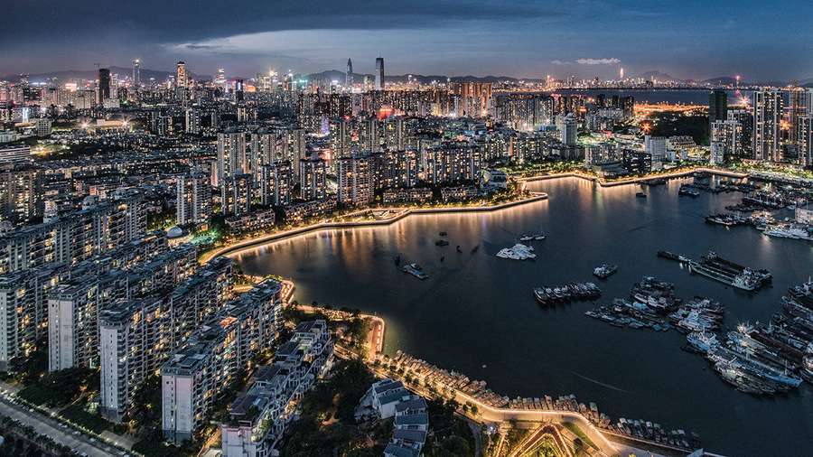City skyline at dusk with illuminated buildings and boats on the water. — Shenzhen Wallpaper