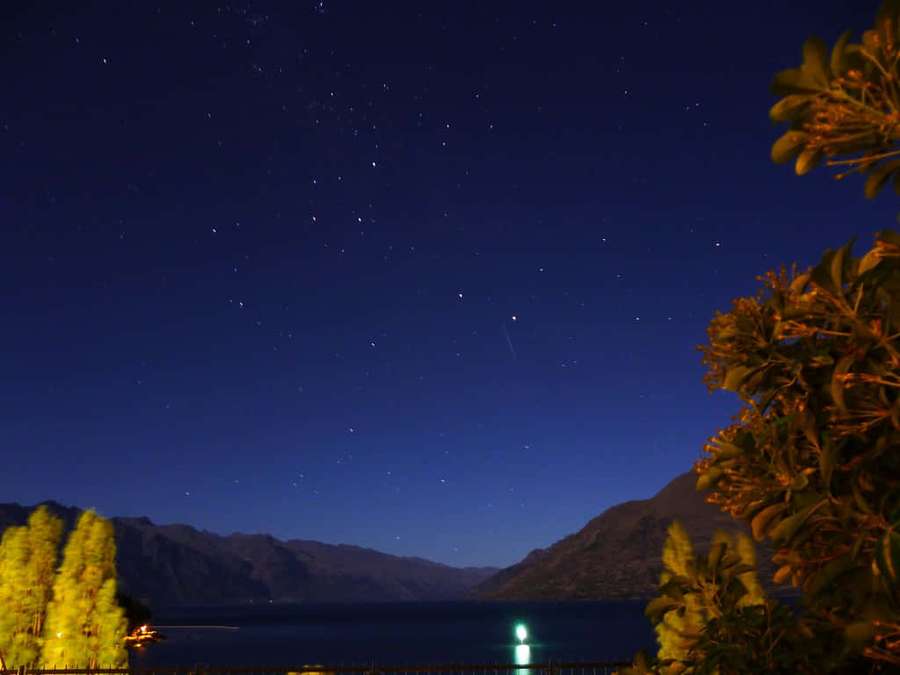Sternennacht über einem See mit Bergen und leuchtenden Bäumen — Sichtbar Wallpaper