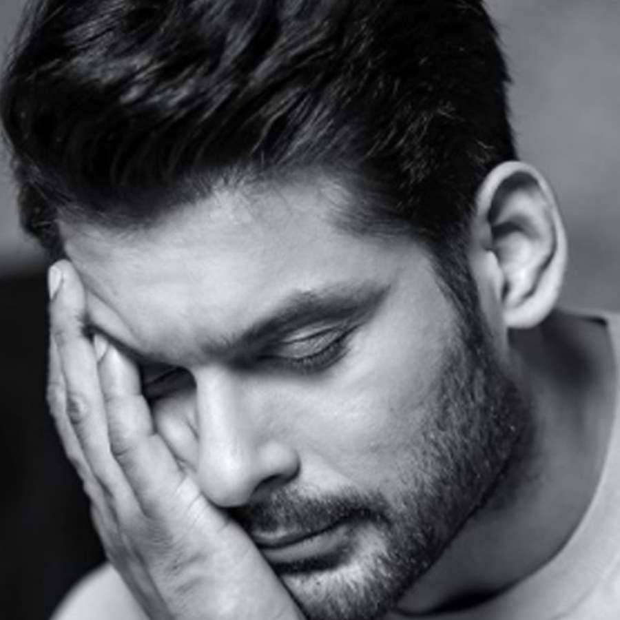 Man resting his head in his hand looking down with a somber expression. — Sidharth Shukla Wallpaper