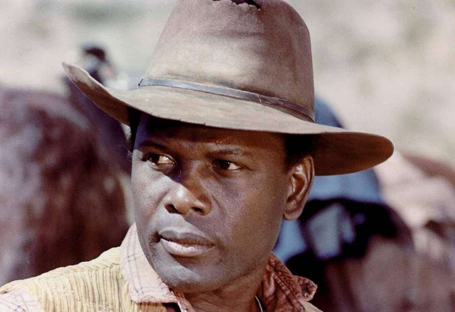 Portrait of a man in a cowboy hat looking intently in a desert setting. — Sidney Poitier Background
