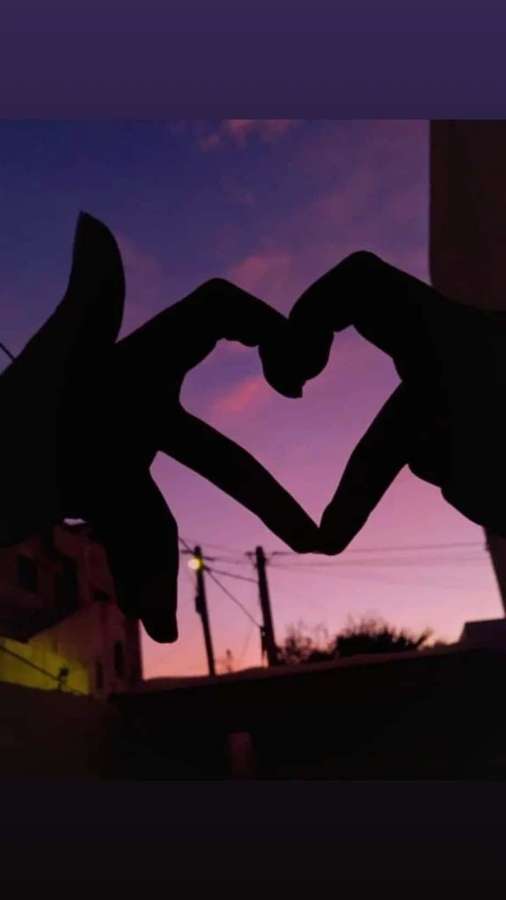 Dos manos formando un corazón contra un cielo crepuscular con edificios al fondo. — Silueta de corazón Fondos de pantalla