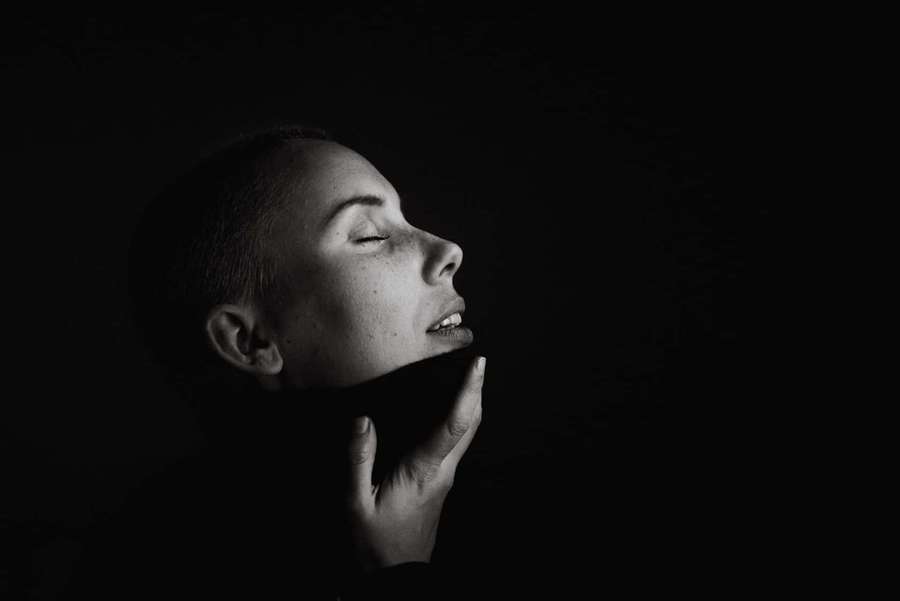 A person with closed eyes and hand on chin in a dark setting. — Simple Dark Wallpaper