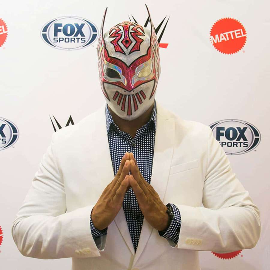 Luchador de terno branco com mãos juntas no peito em evento. — Sin Cara Papéis de Parede