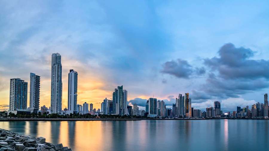 City skyline at sunset with skyscrapers reflecting in calm water. — Skyline Background