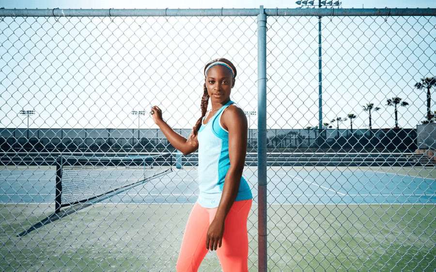 Athletic woman posing by tennis court fence under bright sun. — Sloane stephens Wallpaper