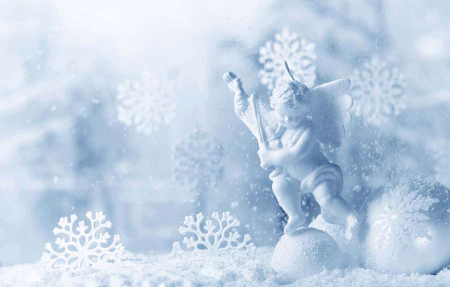 White angel figurine playing trumpet in snowy winter scene with snowflakes and ornaments. — Snow Angel Wallpaper