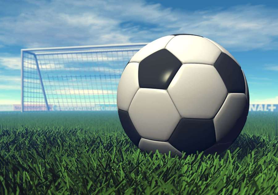Soccer ball on grass field with goal net and blue sky — Soccer Ball Background