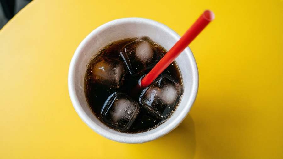 Minimalist flat lay of a foam soda cup with cola and ice on yellow. — Soda Cup Wallpaper