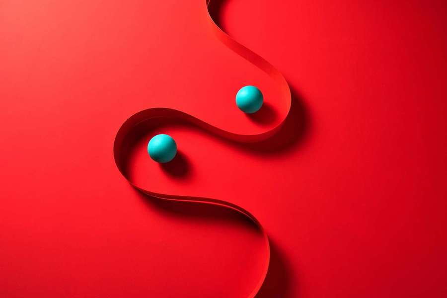 Two teal spheres on a red ribbon against a red background. — Solid Red Picture