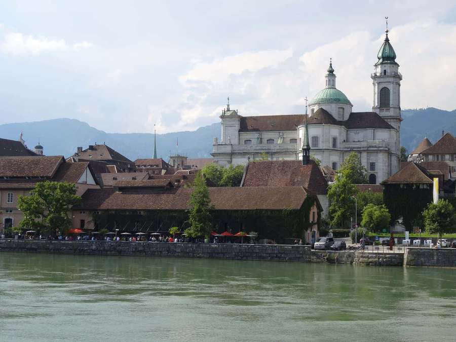 A scenic view of a historic European town along a river with a prominent church. — Solothurn Switzerland Wallpaper