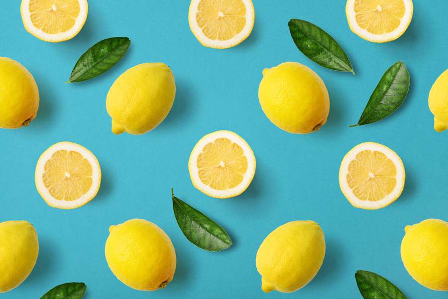Fresh lemons and leaves on a blue background in a flat lay arrangement. — Sour Background