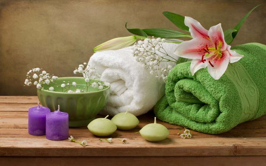 Spa setup with towels lilies candles and flowers on wooden table — Spa Background