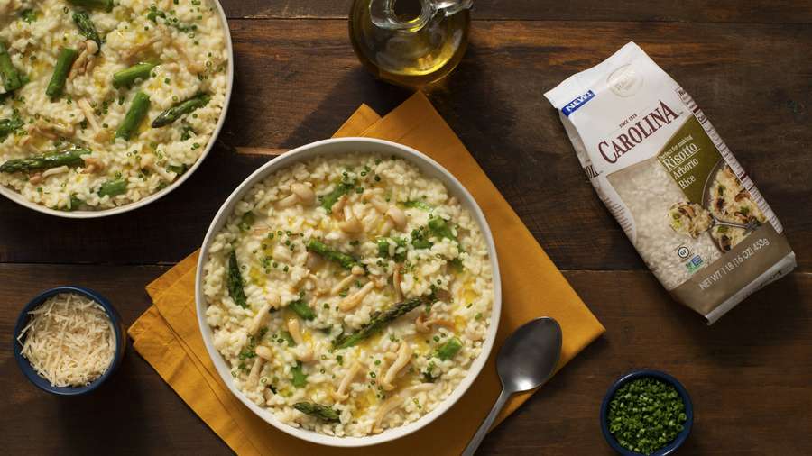 Zwei Schalen mit Spargelrisotto mit Pilzen und Kräutern auf einem Holztisch. — Spargel Wallpaper