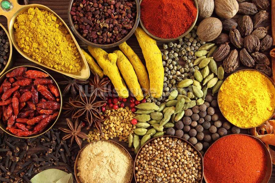 A colorful collection of whole and ground spices in bowls on a wooden table. — Spice Background