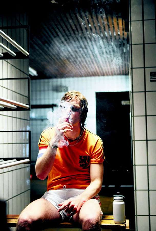 Mann in orangefarbenem Hemd raucht in gefliestem Umkleideraum — Spiegelbilder Hintergrund Wallpaper