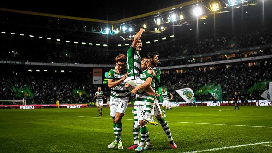 Soccer players celebrating a goal in a packed stadium at night. — Sporting Cp Wallpaper