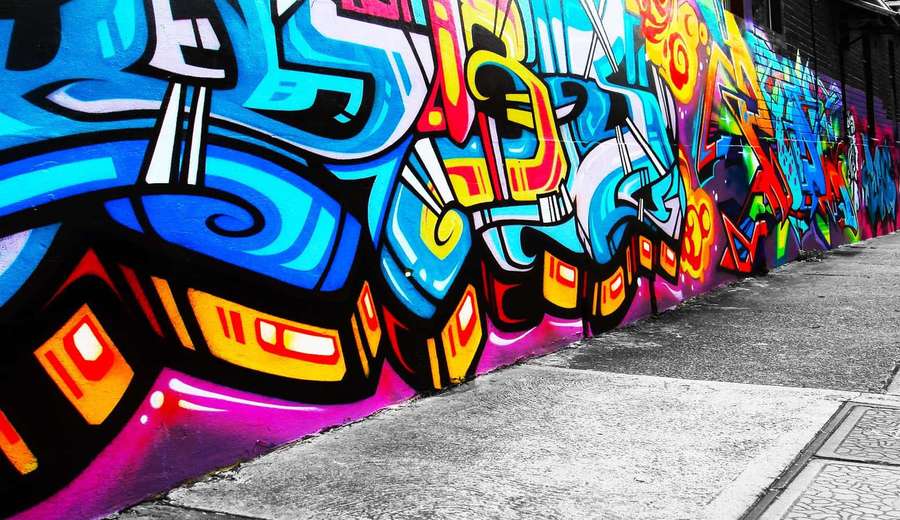 Colorful graffiti mural on city wall beside sidewalk — Spray Paint Background
