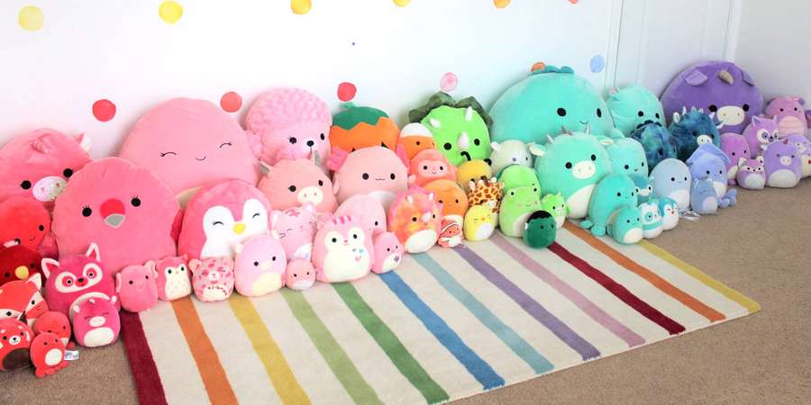 A rainbow rug with a row of colorful plush toys against a polka-dotted wall. — Squishmallows Background
