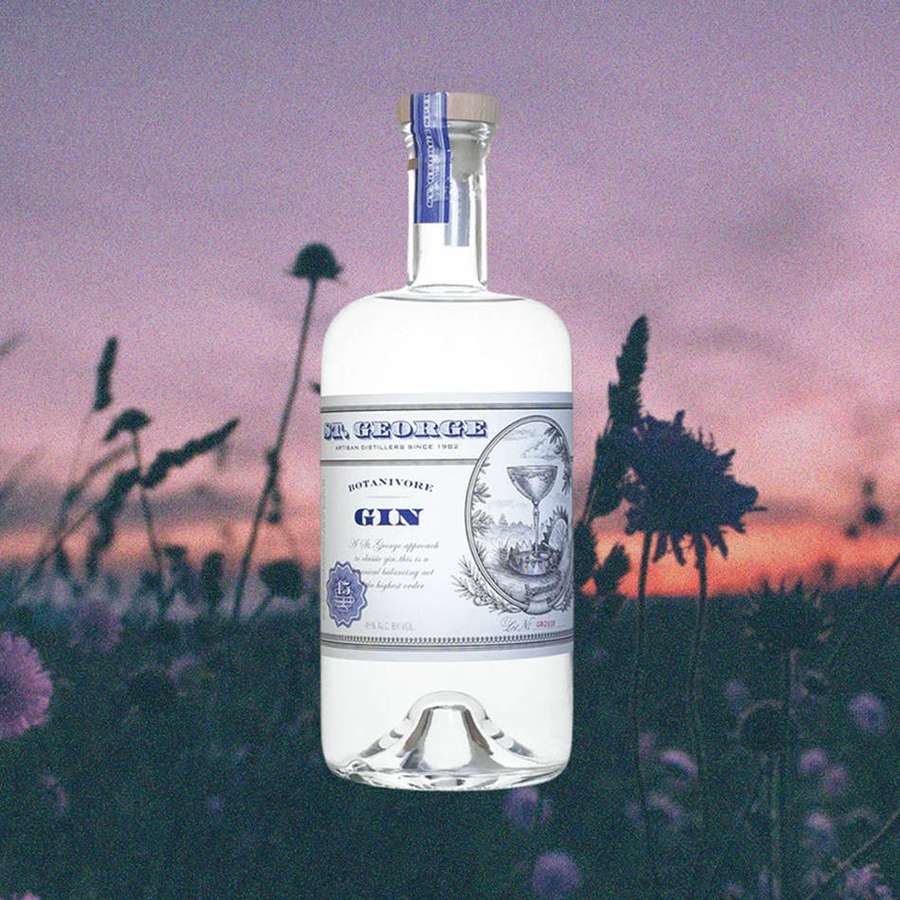 A gin bottle in a field of purple flowers at sunset. — St George Background