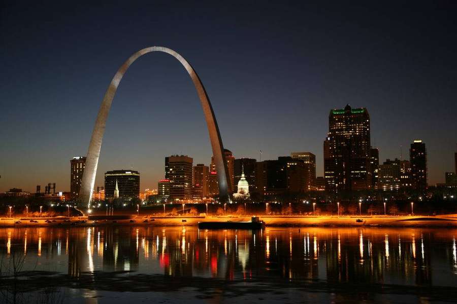 Gateway Arch illuminated at dusk with city lights reflecting on the river. — St. Louis Wallpaper