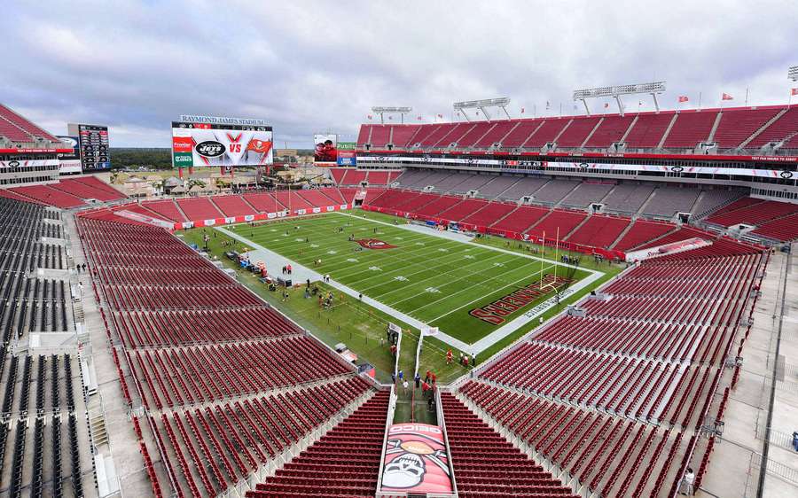 Raymond James Stadium avec des sièges rouges vides et un terrain vert sous un ciel nuageux. — Stadium Fonds d'écran