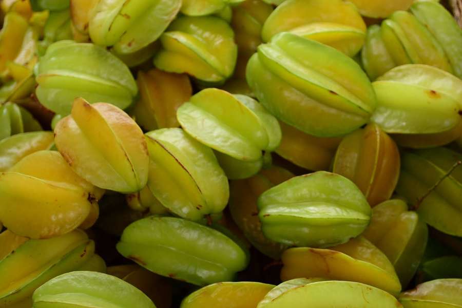 Pile of fresh star fruits with green and yellow hues and ridged surfaces. — Star Fruit Background