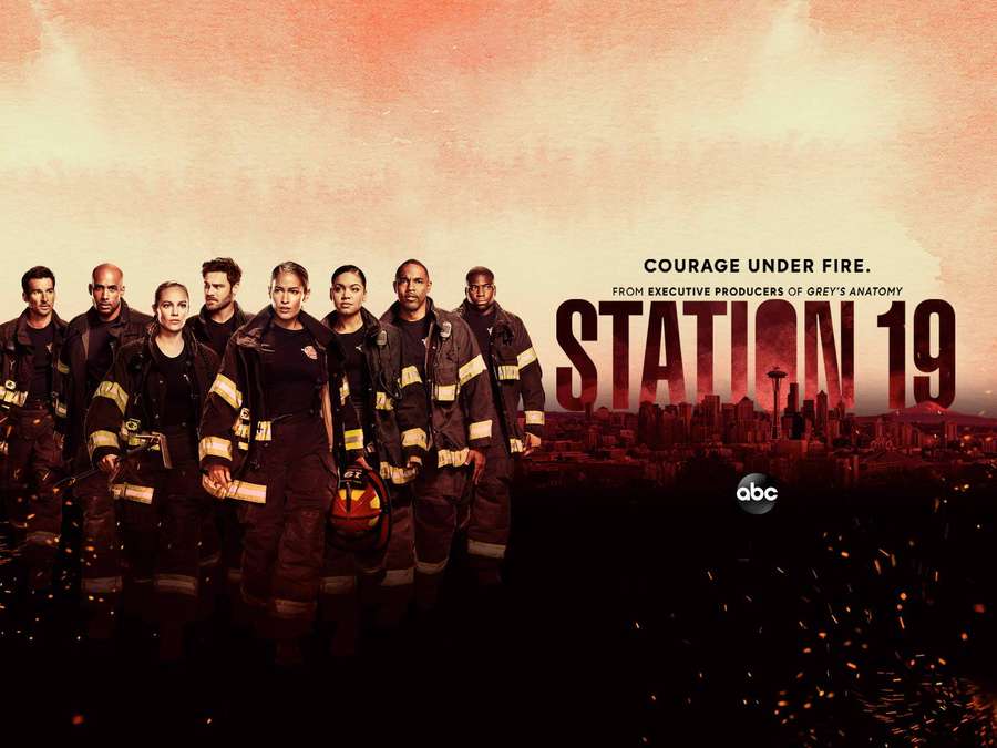 Siete bomberos uniformados están juntos contra un cielo naranja ardiente con un horizonte urbano. — Station 19 Fondos de pantalla