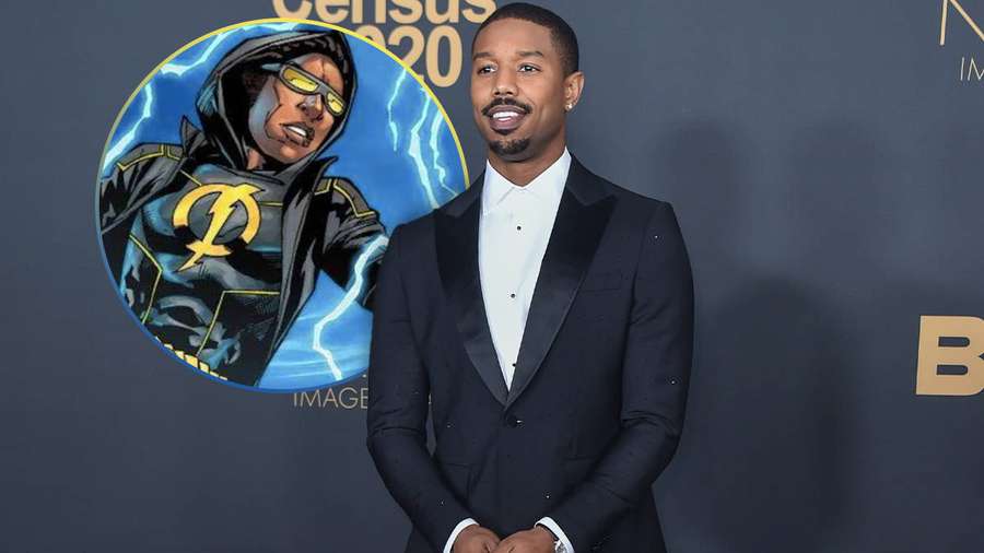 Michael B Jordan in einem schwarzen Smoking bei einer Red-Carpet-Veranstaltung mit einer Superhelden-Grafik hinter ihm. — Statischer Schock Wallpaper