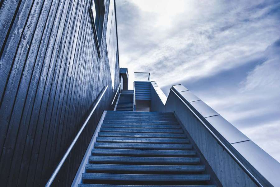 Modern blue staircase leading upward toward a cloudy sky. — Steep Picture