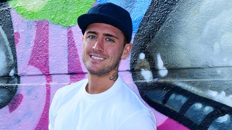 Young man wearing cap and tshirt smiling in front of colorful graffiti wall. — Stephen Bear Wallpaper