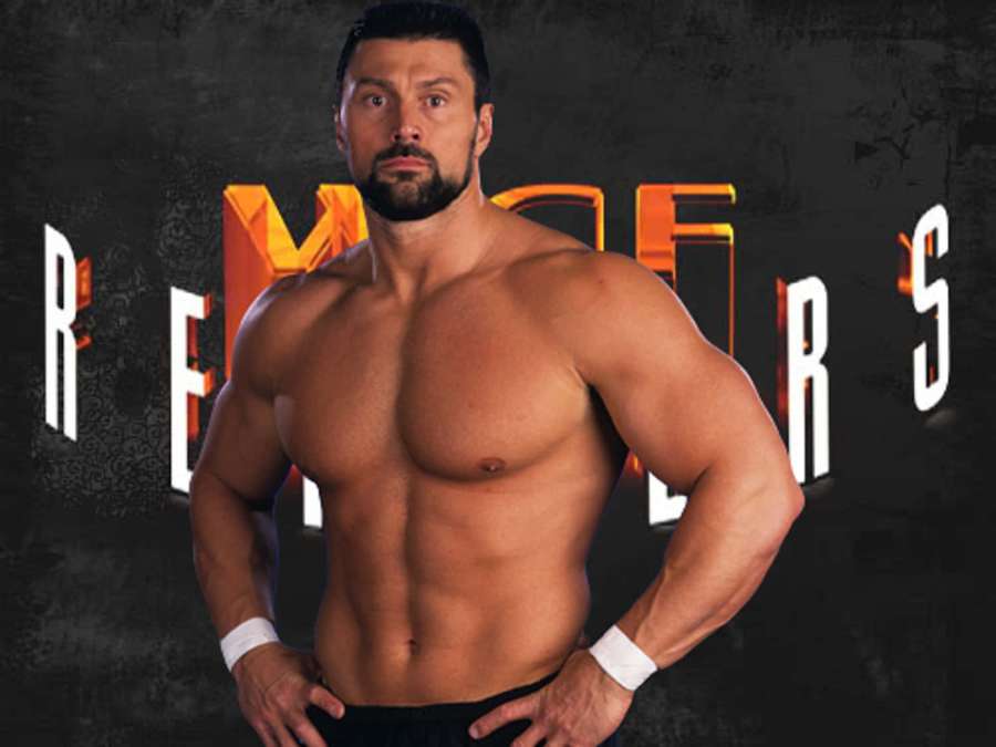 A muscular bearded man in wrestling gear poses confidently against a dark wall with glowing text. — Steve Blackman Wallpaper