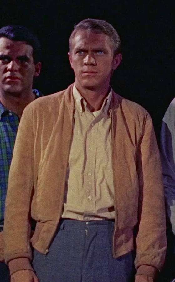 A man in a tan jacket and yellow shirt with a serious expression in a dark studio setting. — Steve Mcqueen Wallpaper