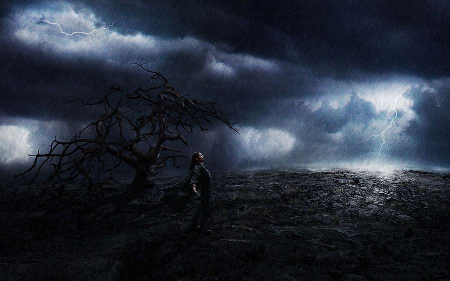 A person stands in a stormy field under a dead tree with lightning flashing in the sky. — Storm Background