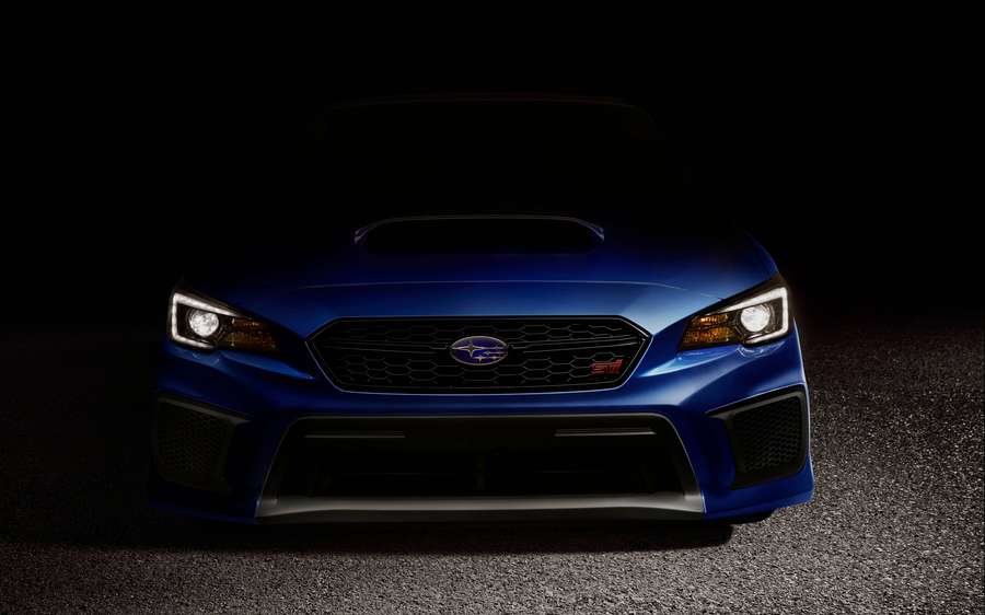Blaue Subaru WRX STI Frontansicht mit leuchtenden Scheinwerfern in dunkler Studioumgebung. — Subaru Bilder