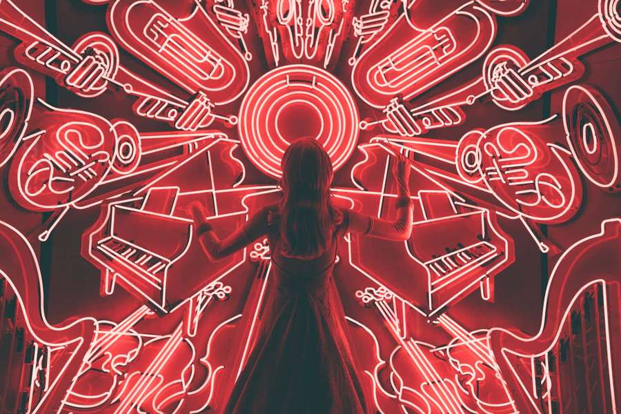 Person surrounded by glowing red neon musical instruments. — Subliminal Wallpaper