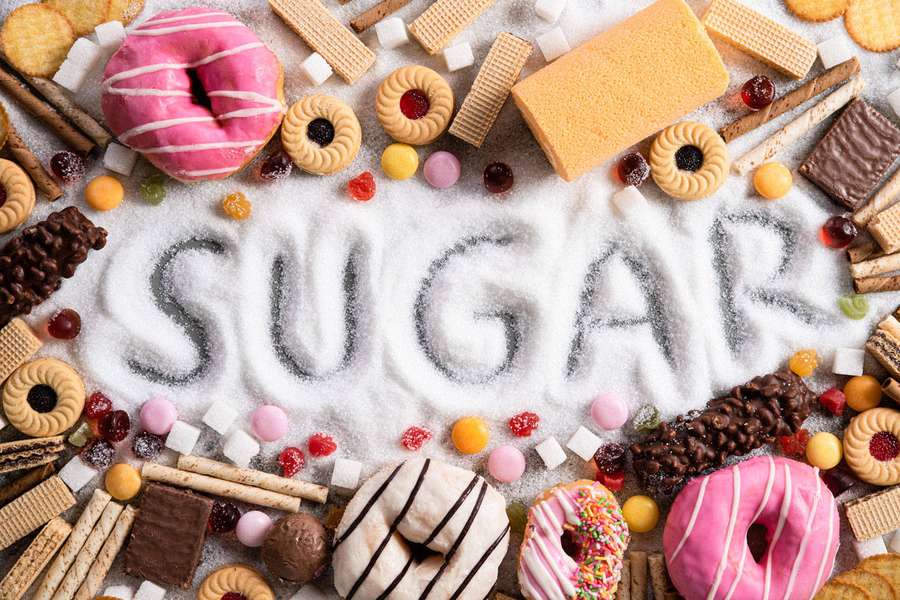 Sugary snacks arranged around the word sugar written in granulated sugar. — Sugar Background