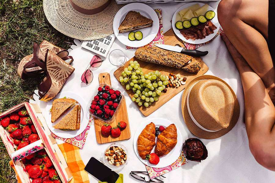 A sunny outdoor picnic with fresh fruit bread and hats on a grassy blanket. — Summer Desktop Wallpaper