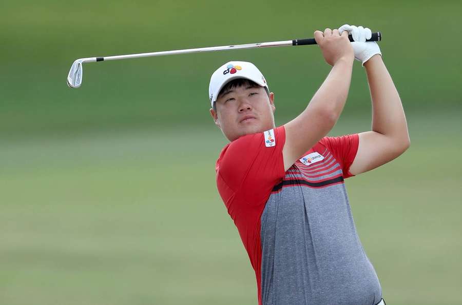Golfista en medio del swing en un campo de golf verde vistiendo camisa roja y gris. — Sungjae Im Fondos de pantalla