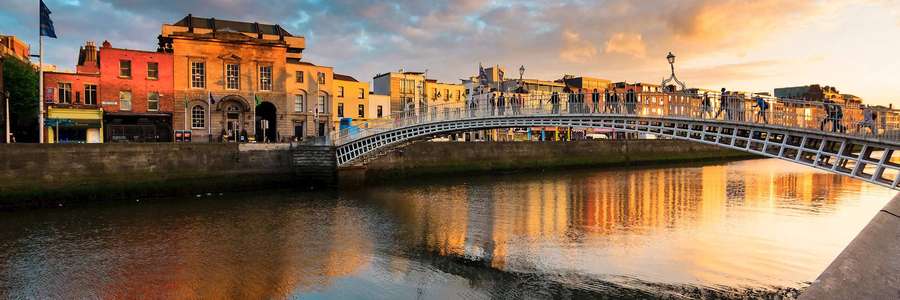 Ha'penny Bridge over a river at golden sunset with historic buildings along the banks. — Super High Resolution Background