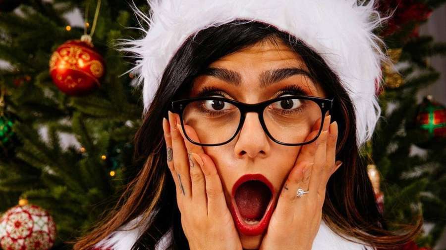 Mulher com gorro de Papai Noel e óculos arfa de surpresa perto da árvore de Natal. — Surpreso Papéis de Parede