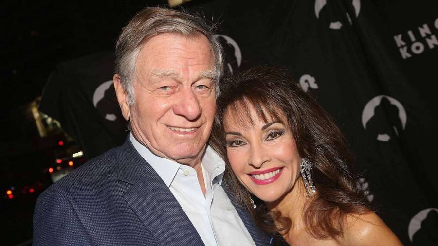 An older man and woman smiling together at a nighttime event. — Susan Lucci Background